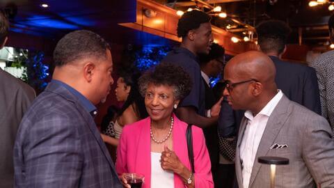 Female event guest explaining something to two men